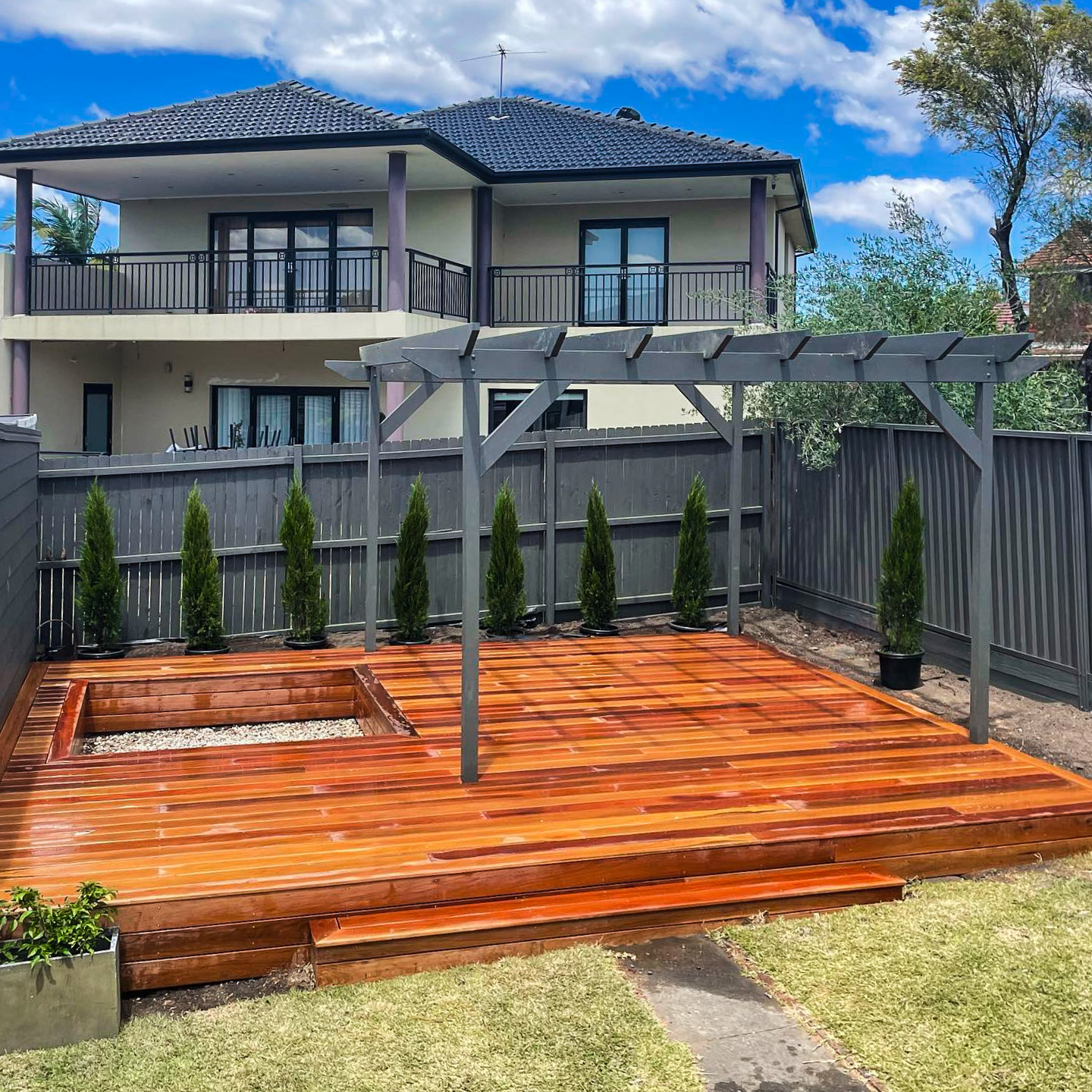 Dark open pergola over a hardwood deck
