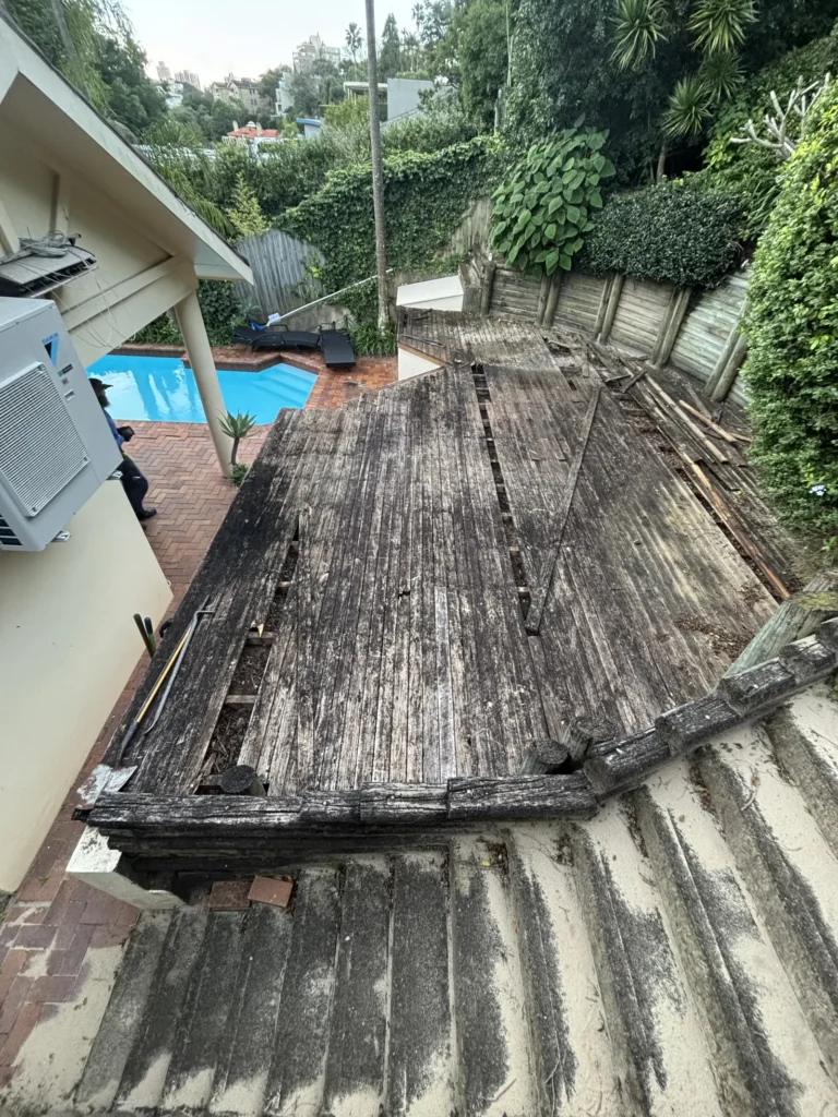 Old timber deck in Double Bay before replacement, boards lifting and gaps through to the dirt