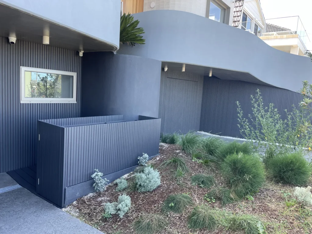 Bin and scooter store at Mons Avenue Maroubra with the gate shut, platform sitting flush with the sloping curved driveway