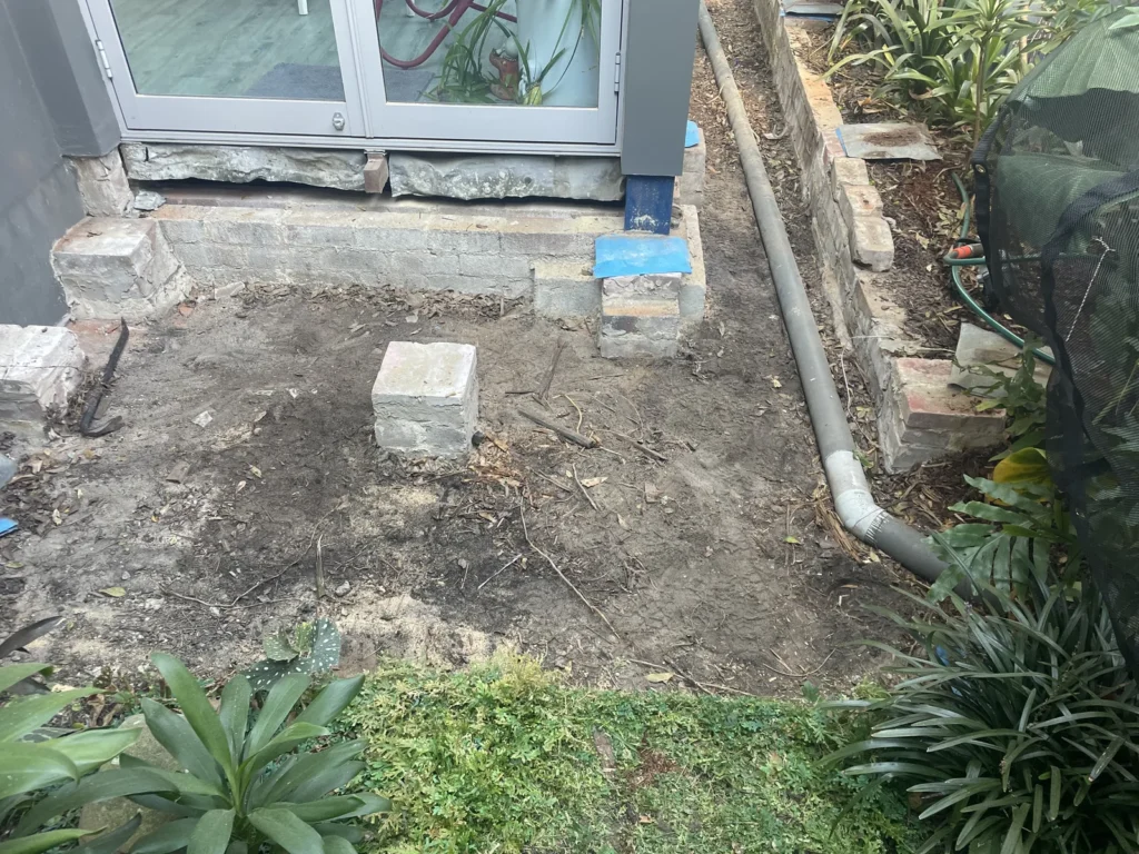 Ground cleared under the old deck in Maroubra showing the existing brick piers kept for reuse
