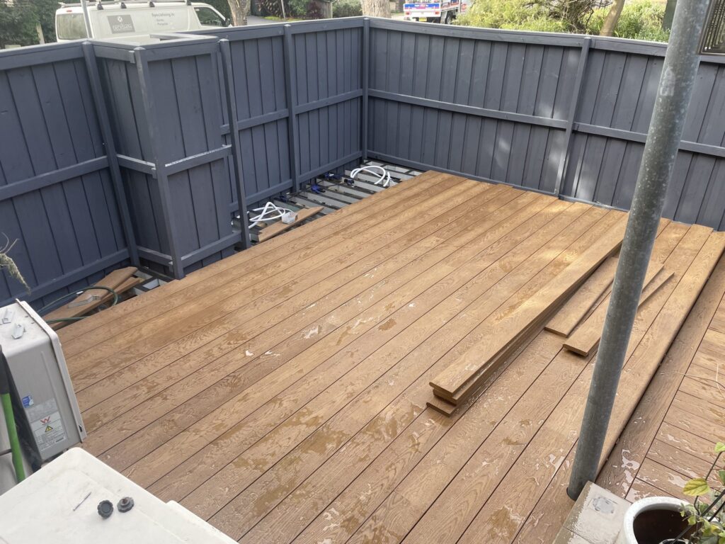 Lower level of a Matraville Millboard deck with boards laid and the subframe still visible at the rear