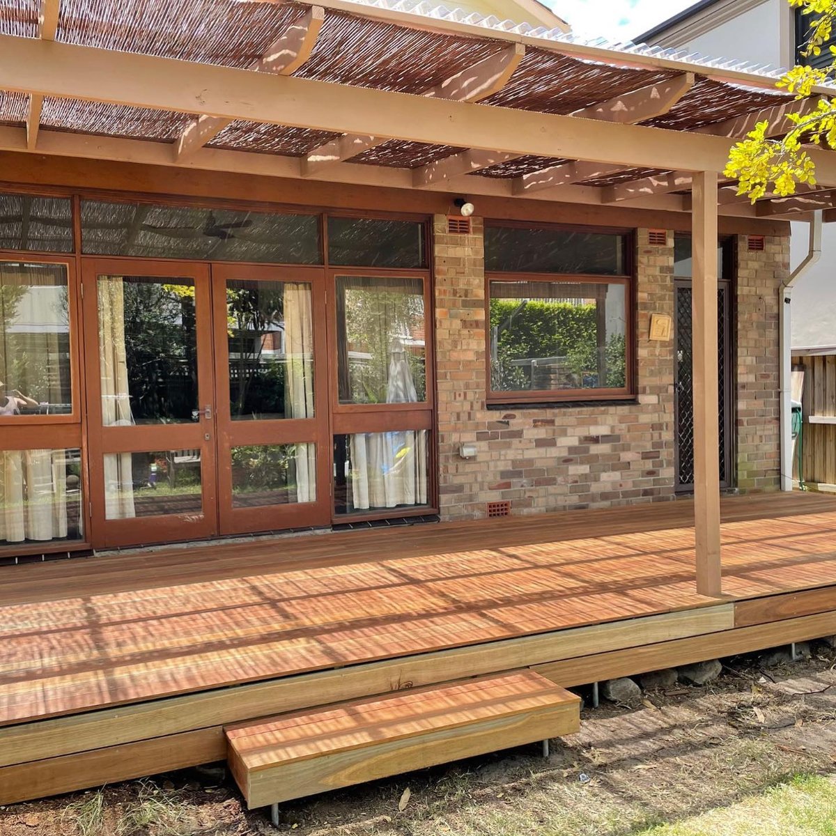 Timber pergola with polycarbonate roof and reed shade screen over a timber deck